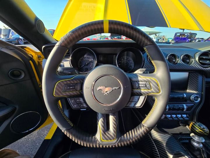 Ford Mustang S550 interior featuring a custom 4x4 matte twill carbon fiber steering wheel with yellow stripe and custom yellow stitching and matching carbon fiber dash trim by UkieCarbon.