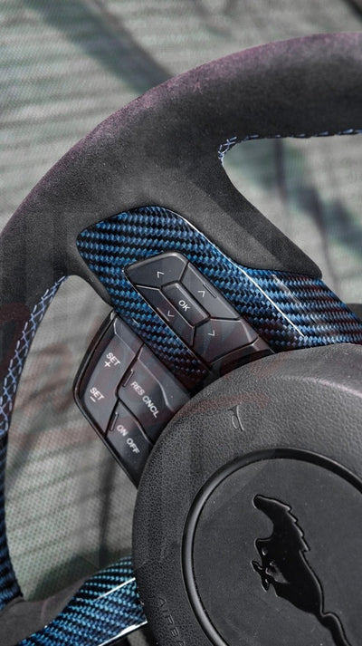 Detail view of blue carbon fiber on a custom 2015-2023 Mustang S550  steering wheel with OEM control buttons.
