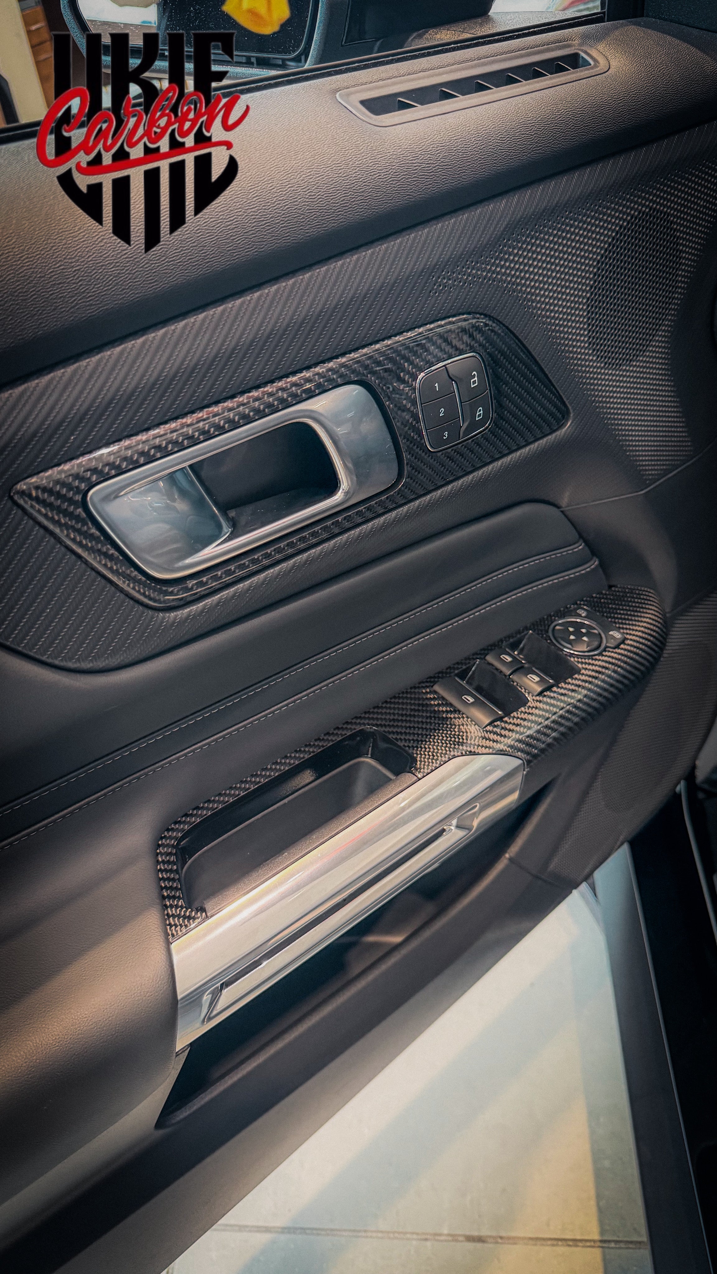 Mustang door panel with carbon fiber trim, handle surround, and window switch bezel installed